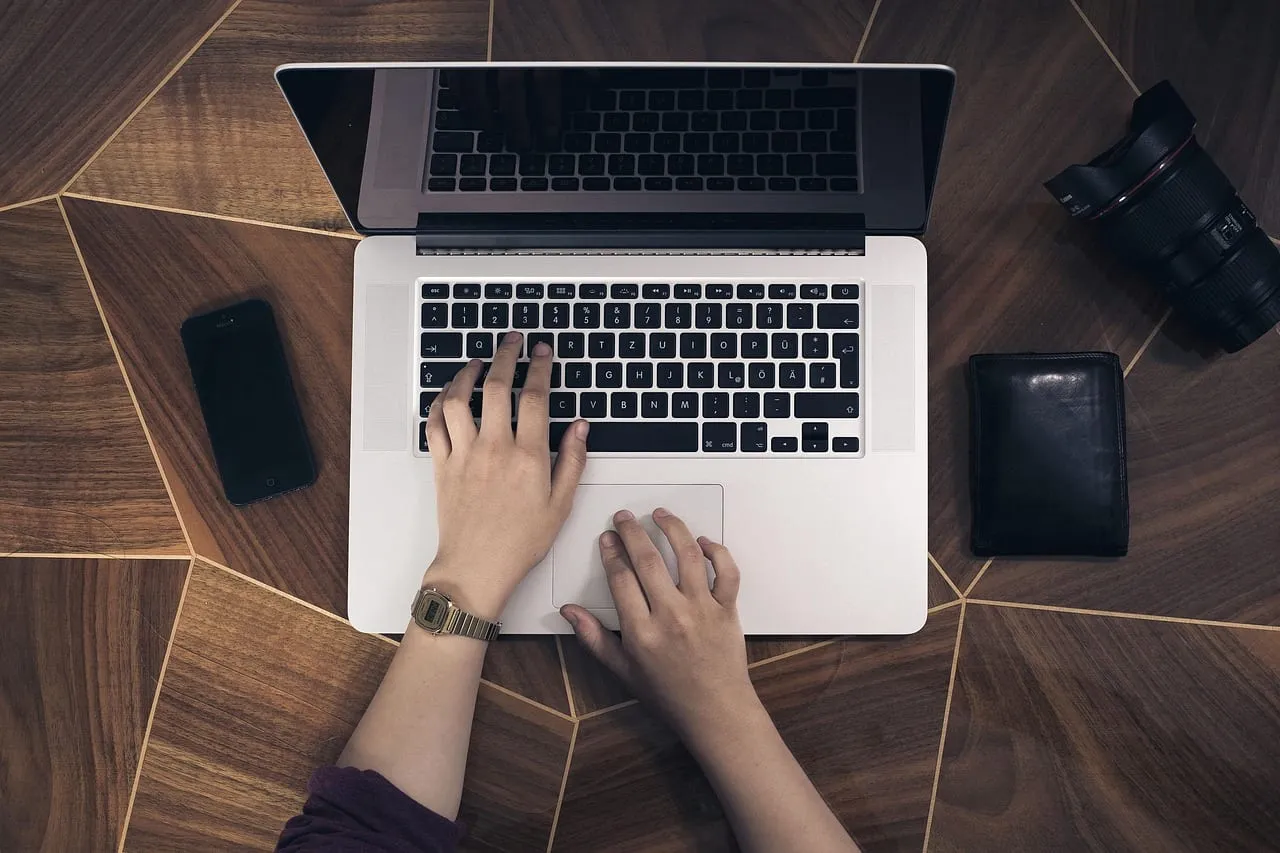 Photo showing laptop, hands, desk and working.