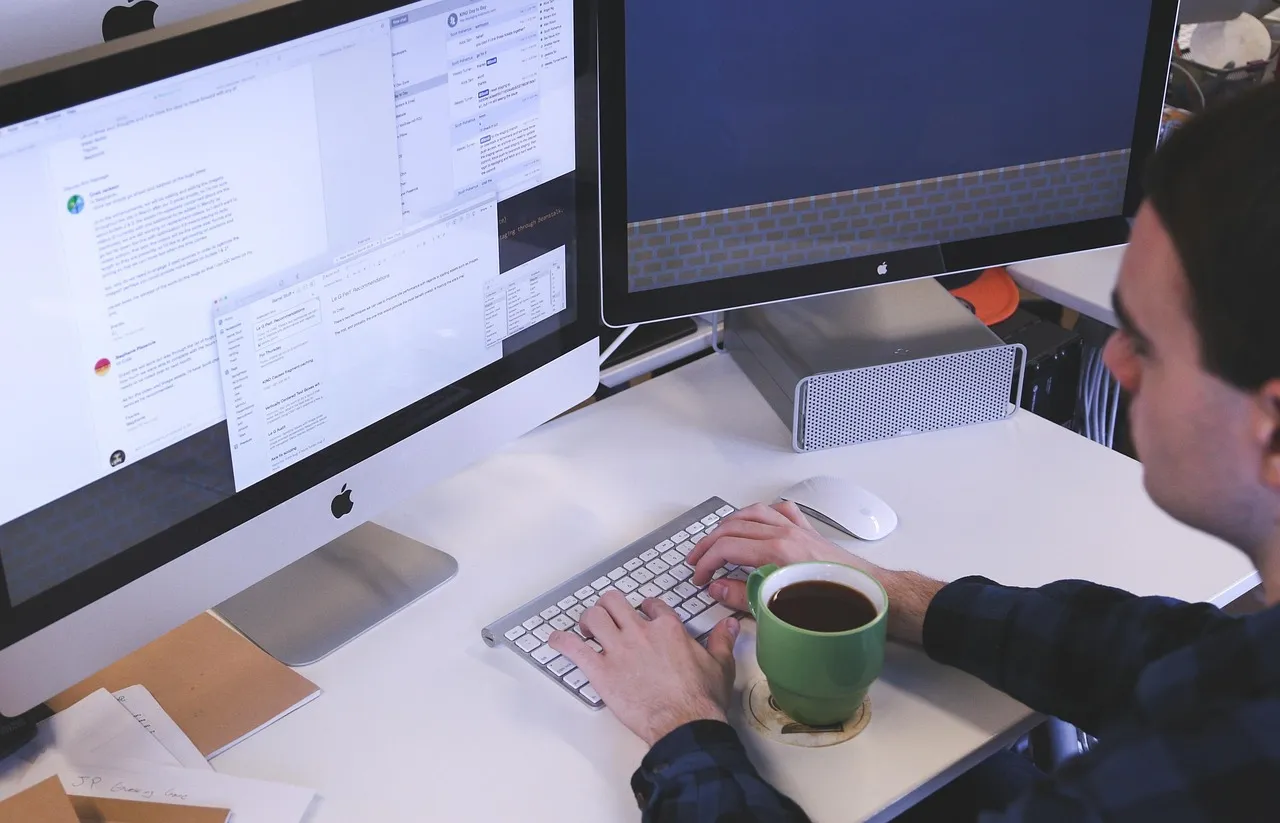 Photo showing typing, computer, man and workspace.