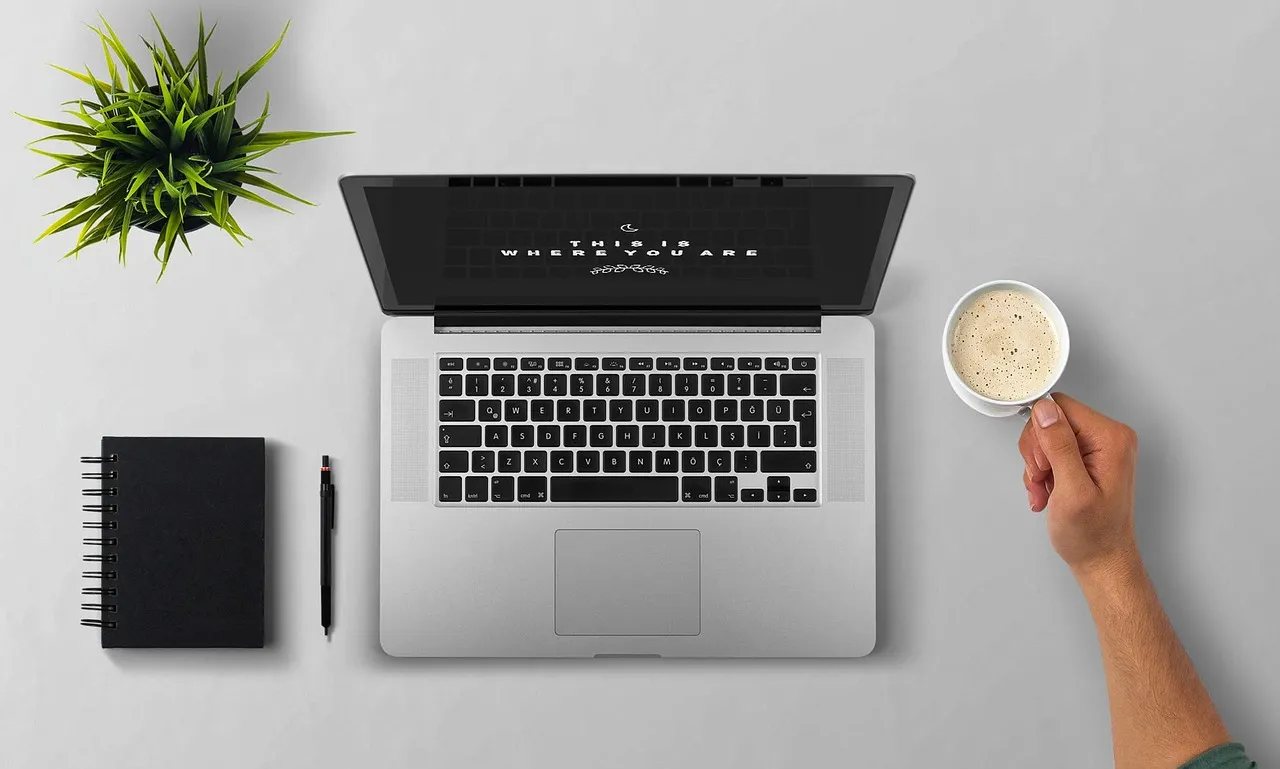 Photo showing laptop, coffee, arm and desktop.