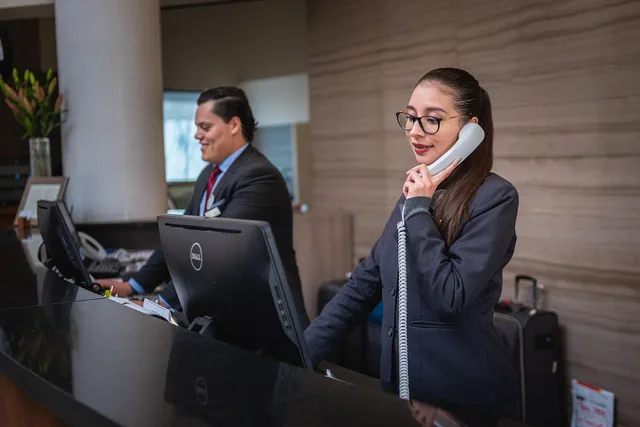 Photo showing receptionists, phone call and hotel.
