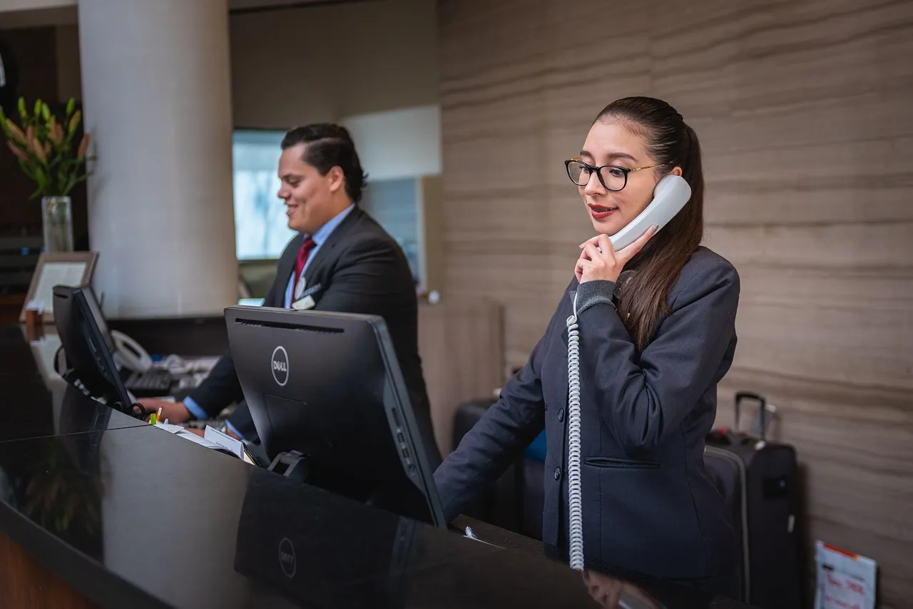 Photo showing receptionists, phone call and hotel.