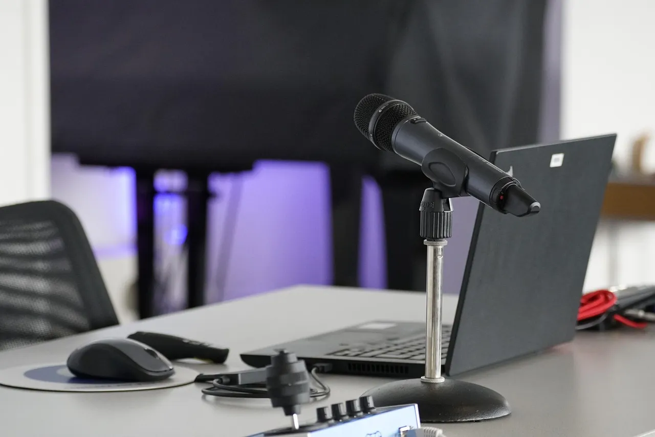 Photo showing laptop, conference table, mouse and work.