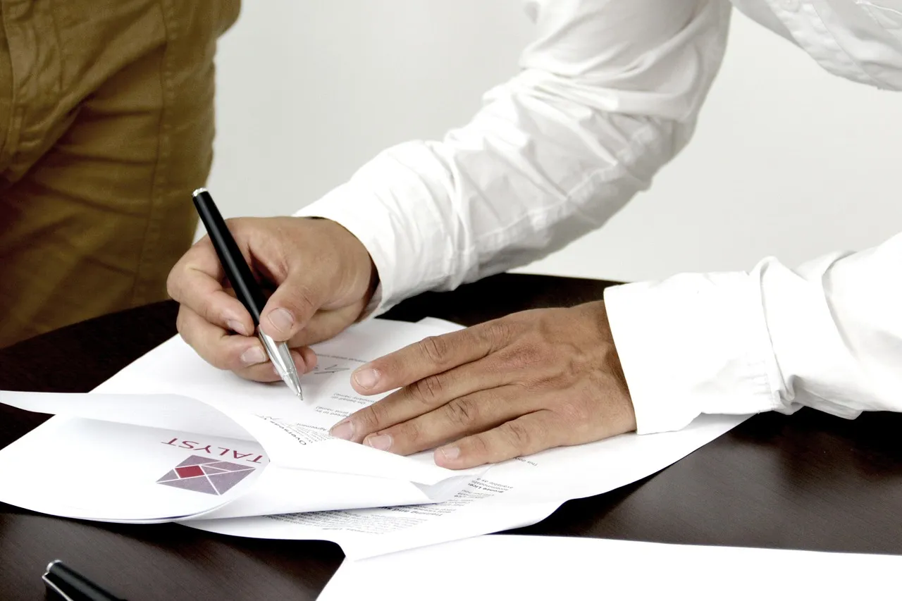 Photo showing firm, contract and person signing a document.