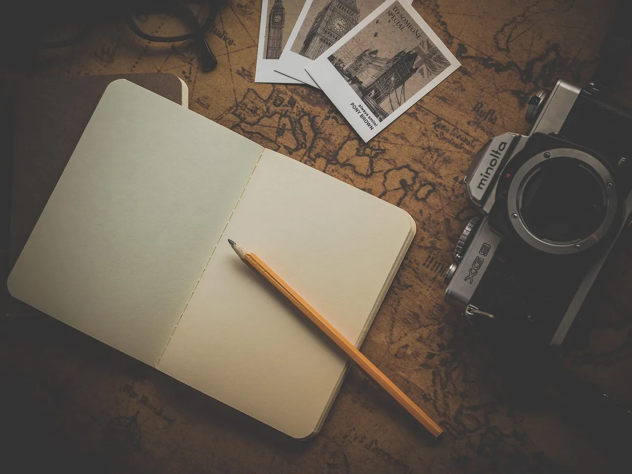 Photo showing notebook, camera, map and pencil.